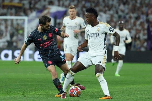 epa11268297 Real Madrid's Vinicius Jr (R) in action against Manchester City's Bernardo Silva (L) during the UEFA Champions League quarter finals first leg soccer match soccer match between Real Madrid and Manchester City, in Madrid, Spain, 09 April 2024.  EPA/Kiko Huesca