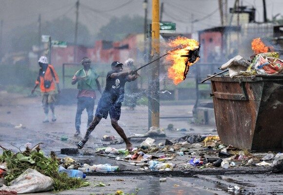 epa11822053 A demonstrator sets fire to a dumpster during a protest on the day of the new parliament's inauguration, in Maputo, Mozambique, 13 January 2025. The swearing-in ceremony of the deputies elected to Mozambique's new parliament, the Assembly of the Republic, is underway as two opposition parties, Renamo and MDM that reject the outcome of the October 2024 election, boycotted the ceremony.  EPA/LUISA NHANTUMBO