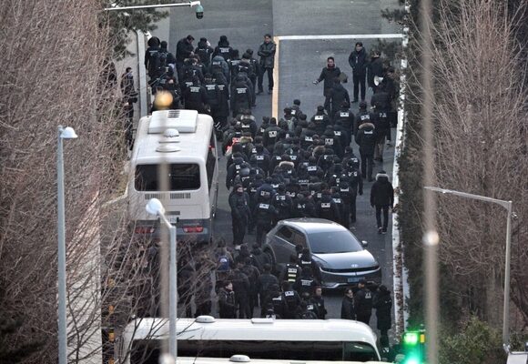 Police officers enter the compound of the presidential residence of impeached South Korea President Yoon Suk Yeol in Seoul, as seen from a hill, on January 15, 2025. South Korea's Constitutional Court opened the impeachment trial of President Yoon Suk Yeol on January 14 over his failed martial law bid, but quickly adjourned the first hearing after the suspended leader didn't show up. (Photo by ANTHONY WALLACE / AFP)