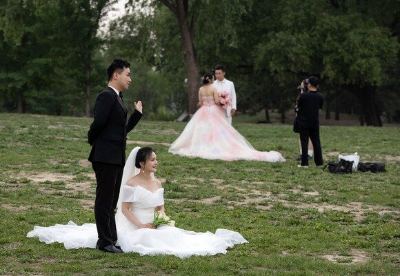 epa12119678 Couples pose for pre-wedding photos in a park on ‘520 Day’ in Beijing, China, 20 May 2025. In China, the date 20 May is an unofficial Valentine’s Day known as '520 Day' because the pronunciation of 'five two zero' (520) sounds similar to 'I love you' in Mandarin. The day is marked by gift-giving and expressions of love.  EPA/JESSICA LEE